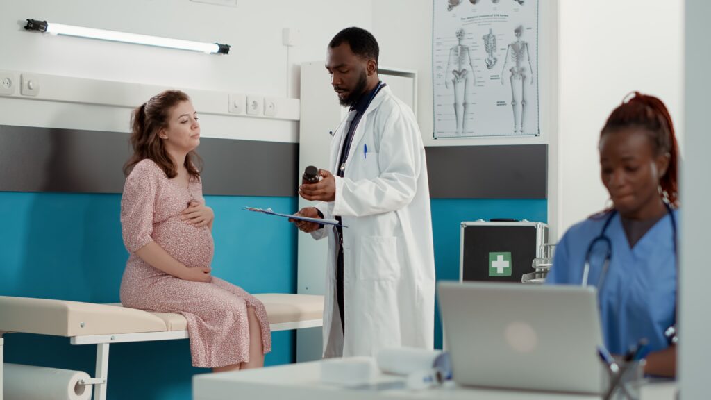 A pregnant woman receives medical consultation from a doctor in a clinic, representing maternal health care under Linda Mama vs SHA in Kenya
