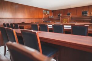 Empty wooden courtroom with rows of chairs and desks facing the judge’s bench, symbolising justice, legal proceedings, and judicial institutions.
