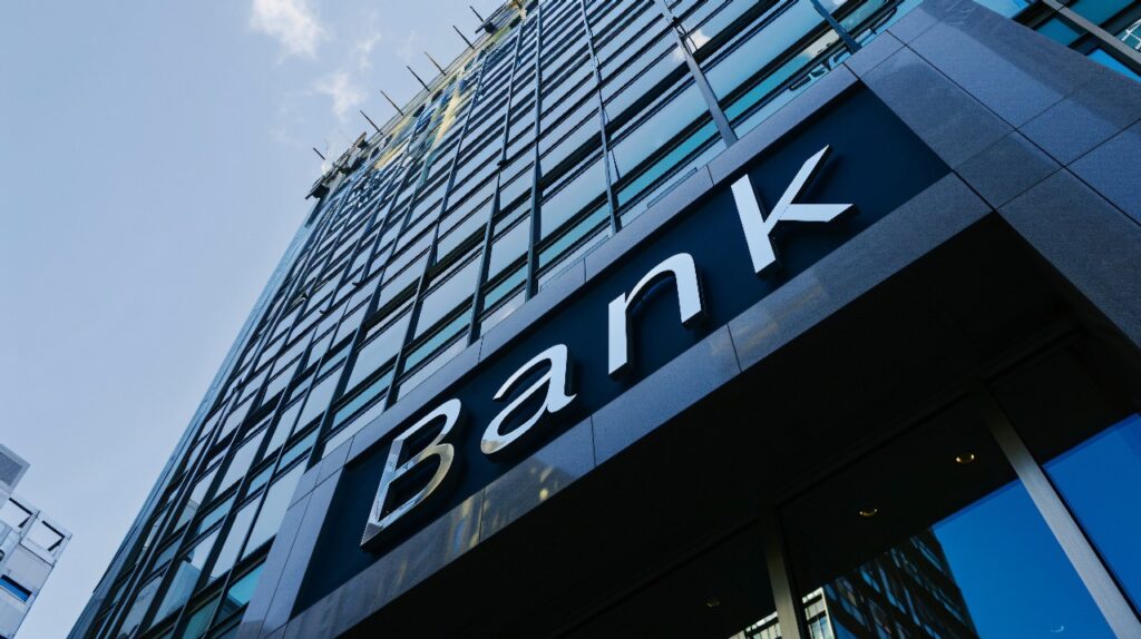Tall glass building with a large sign reading Bank on the facade, representing a financial institution.